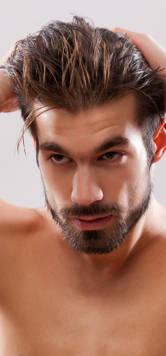 immagine di un uomo che si tocca i capelli con appena messa la cera nei capelli abbastanza lunghi